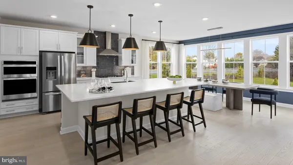 a kitchen with stainless steel appliances granite countertop a stove a refrigerator a kitchen island a table and chairs
