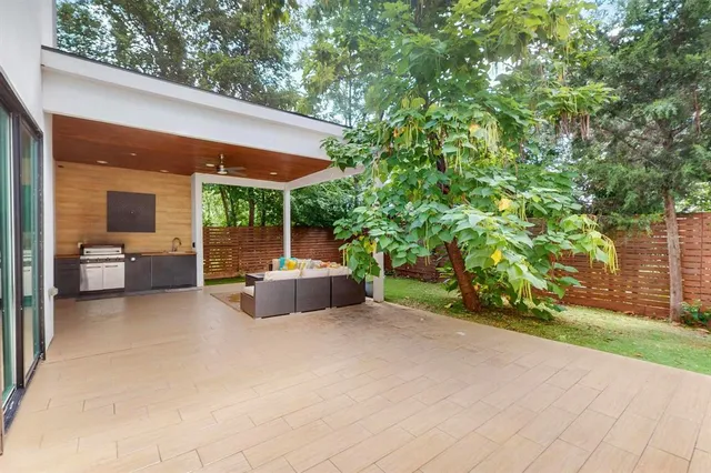 a view of a patio with table and chairs under an umbrella with large trees