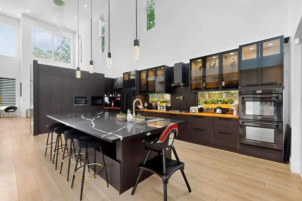 a kitchen with stainless steel appliances granite countertop a stove a refrigerator a sink a dining table and chairs with wooden floor