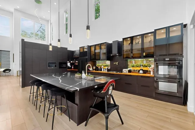 a kitchen with stainless steel appliances granite countertop a stove a refrigerator a sink a dining table and chairs with wooden floor