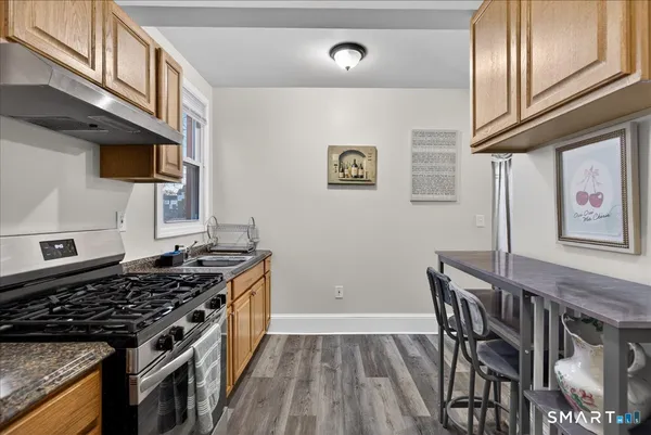 a kitchen with stainless steel appliances granite countertop a stove top oven a dining table and chairs with wooden floor