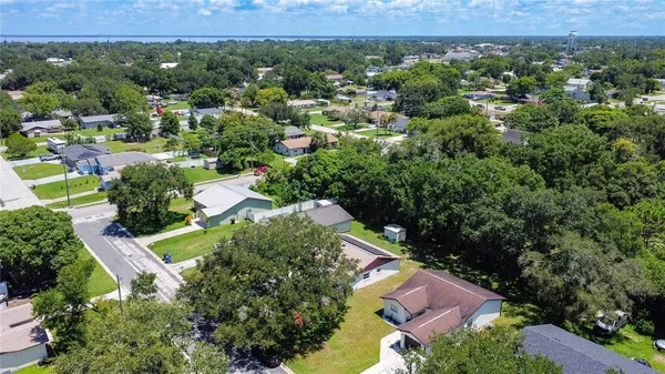 an aerial view of residential houses with outdoor space and trees