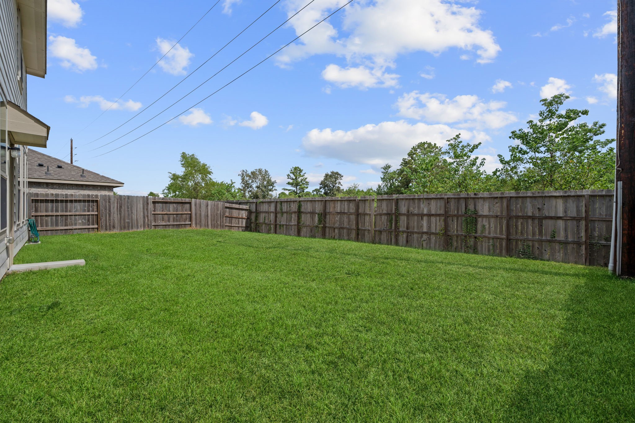 3043 Marble Rise Trail Porter, TX 77365 - Photo 25 of 27 Expansive backyard with lush green grass, perfect for outdoor activities and relaxation, enclosed by a wooden privacy fence.