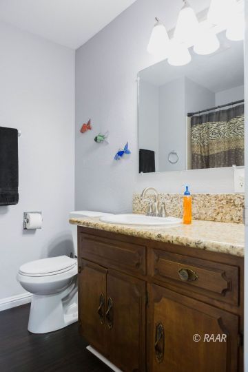 117 South Fire Opal Street Ridgecrest, CA 93555 - Photo 23 of 28 a bathroom with a granite countertop toilet sink and mirror