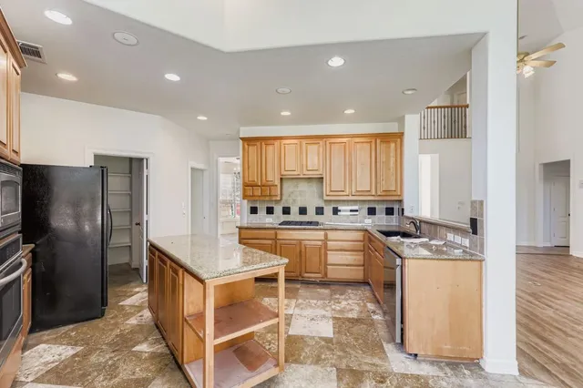 a large kitchen with stainless steel appliances granite countertop a sink and cabinets
