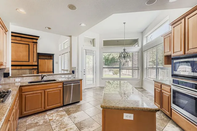 a large kitchen with kitchen island granite countertop a sink and a stove