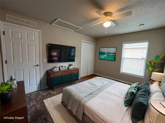 a bedroom with a bed television window and a potted plant