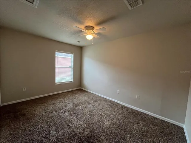 an empty room with a window and a fan