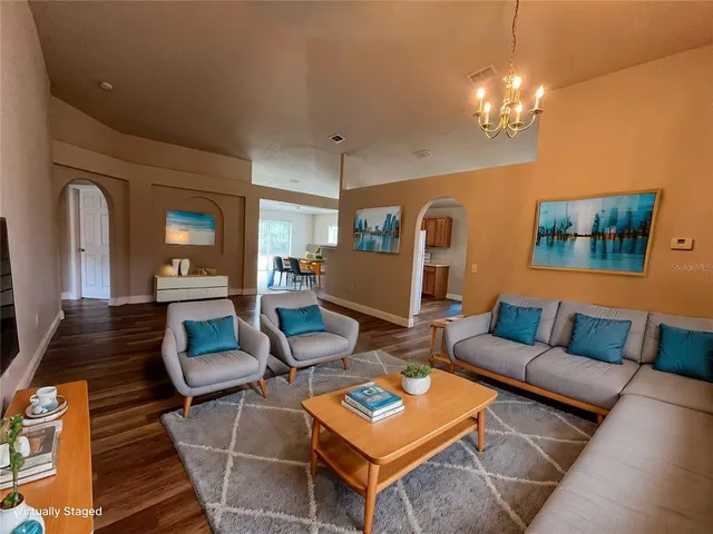a living room with furniture a chandelier and a mirror