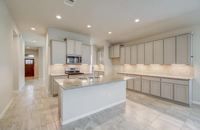 a kitchen with granite countertop a sink and white cabinets