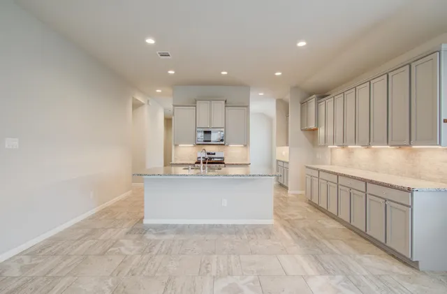 a kitchen with granite countertop a sink and white cabinets