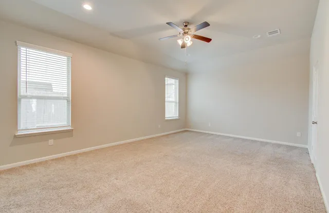 an empty room with chandelier fan and windows