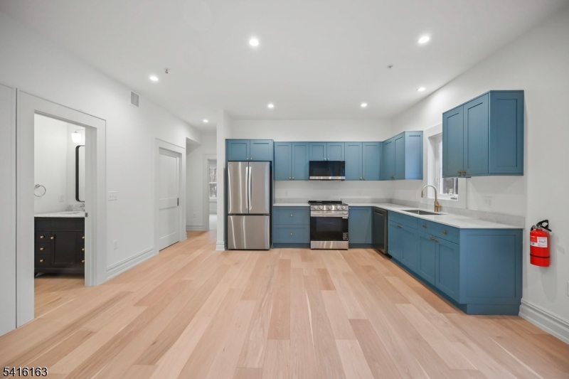 1209 Littleton Road, Unit B Morris Plains, NJ 07950 - Photo 11 of 19 a large kitchen with stainless steel appliances kitchen island a sink dishwasher a refrigerator and a oven with wooden floor