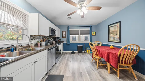 a kitchen with stainless steel appliances granite countertop a stove top oven a sink dishwasher a dining table and chairs with wooden floor