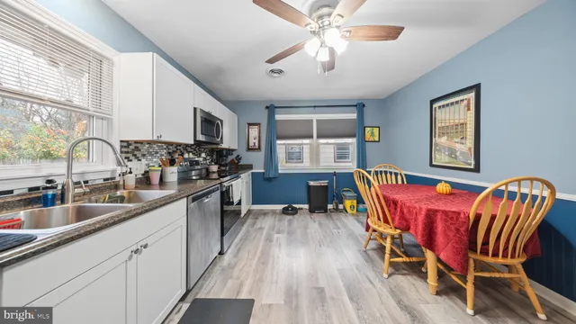 a kitchen with stainless steel appliances granite countertop a stove top oven a sink dishwasher a dining table and chairs with wooden floor