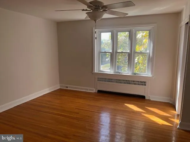 an empty room with wooden floor fan and windows