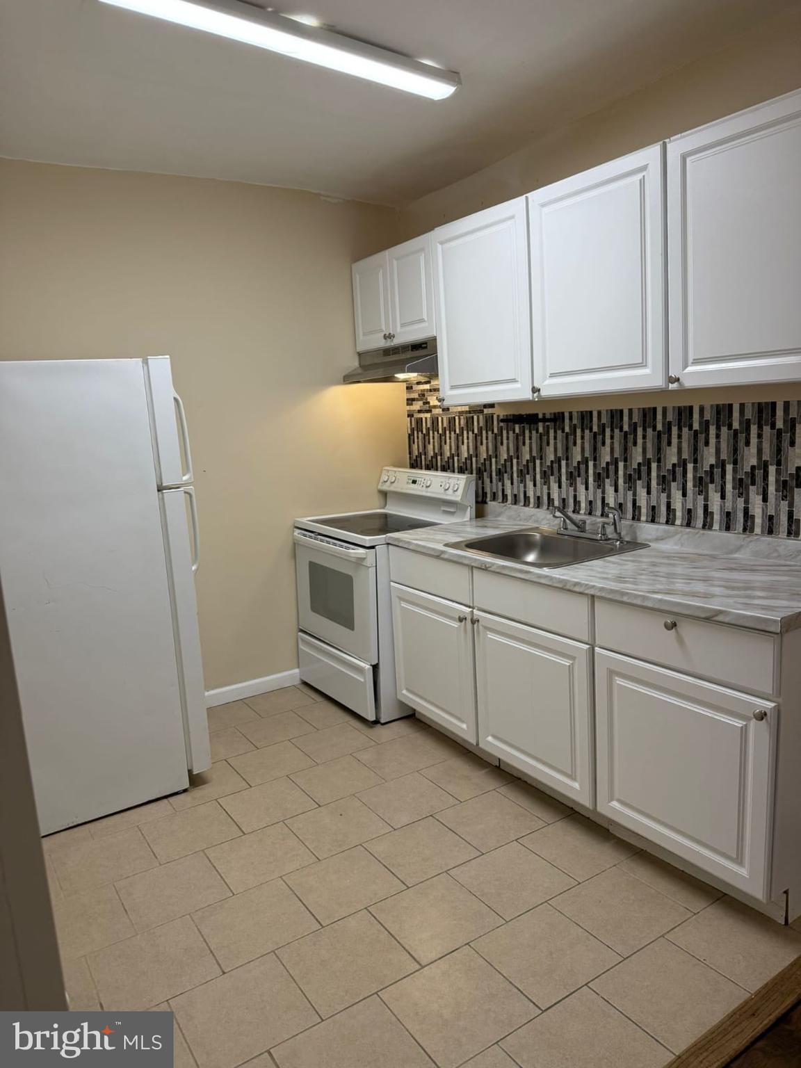 5677 Diamond Street Philadelphia, PA 19131 - Photo 4 of 7 a kitchen with granite countertop cabinets and white appliances