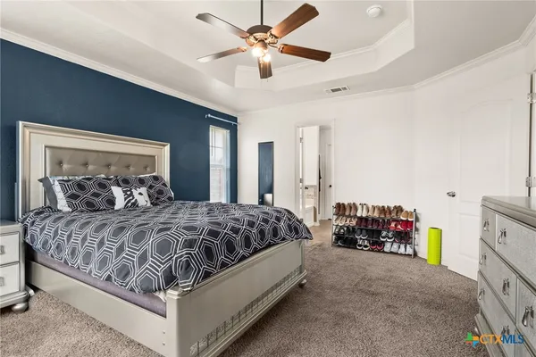 a bedroom with a bed a dresser and a chandelier