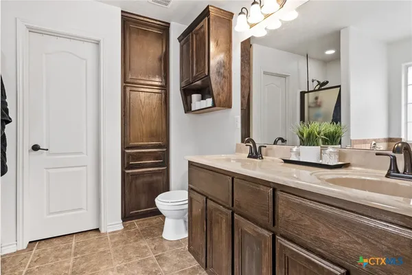a bathroom with a granite countertop sink toilet and mirror