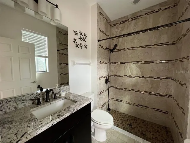 a bathroom with a granite countertop sink toilet and shower