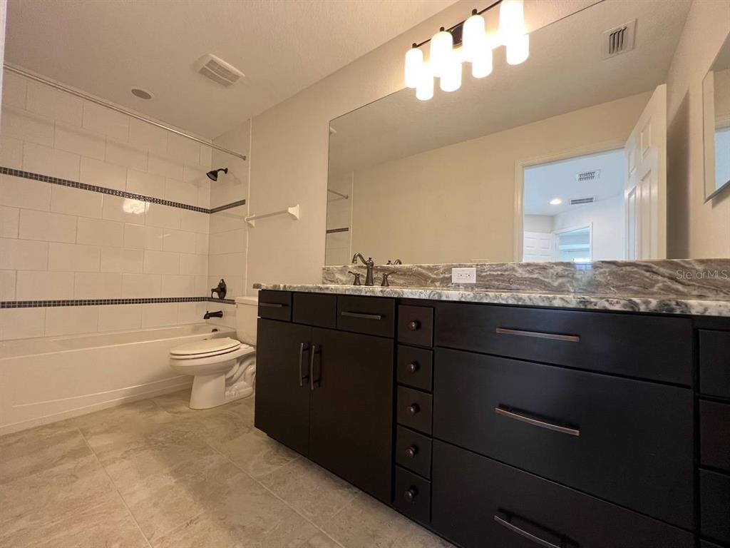 1692 Nature View Drive Lutz, FL 33558 - Photo 40 of 53 a bathroom with a granite countertop toilet sink and a large mirror