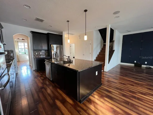 a kitchen with stainless steel appliances granite countertop a sink a stove and a wooden floors