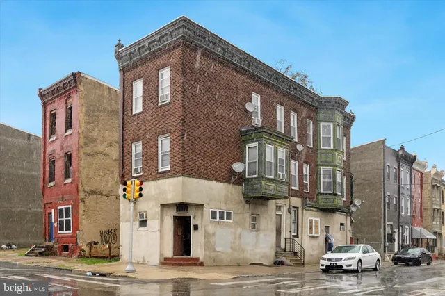 a front view of a building with lot of cars and trees