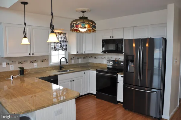 a kitchen with stainless steel appliances granite countertop a refrigerator a stove a sink and a microwave