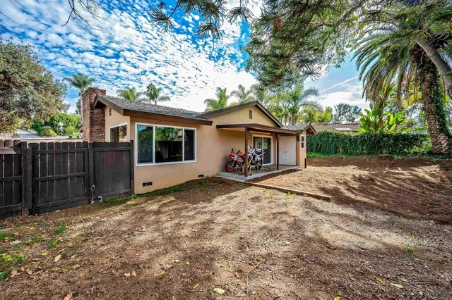 a view of a house with a yard and wooden fence