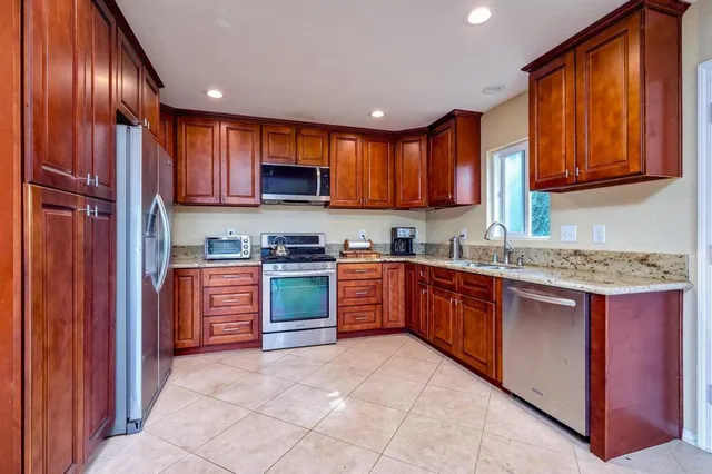 a kitchen with stainless steel appliances granite countertop wooden cabinets a stove top oven a sink and dishwasher