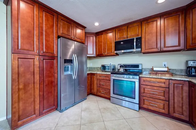 a kitchen with stainless steel appliances granite countertop wooden cabinets and a refrigerator