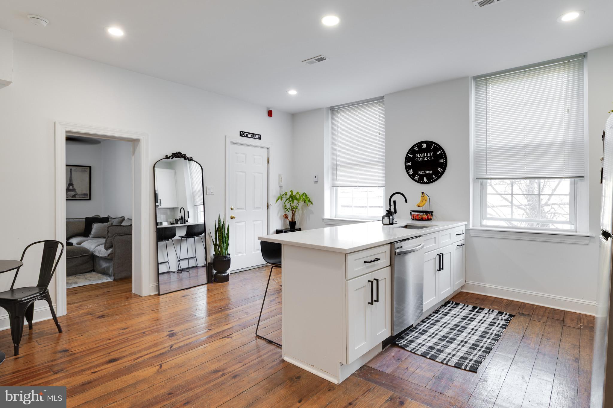 a kitchen with stainless steel appliances a white stove top oven a refrigerator a dining table and chairs with wooden floor