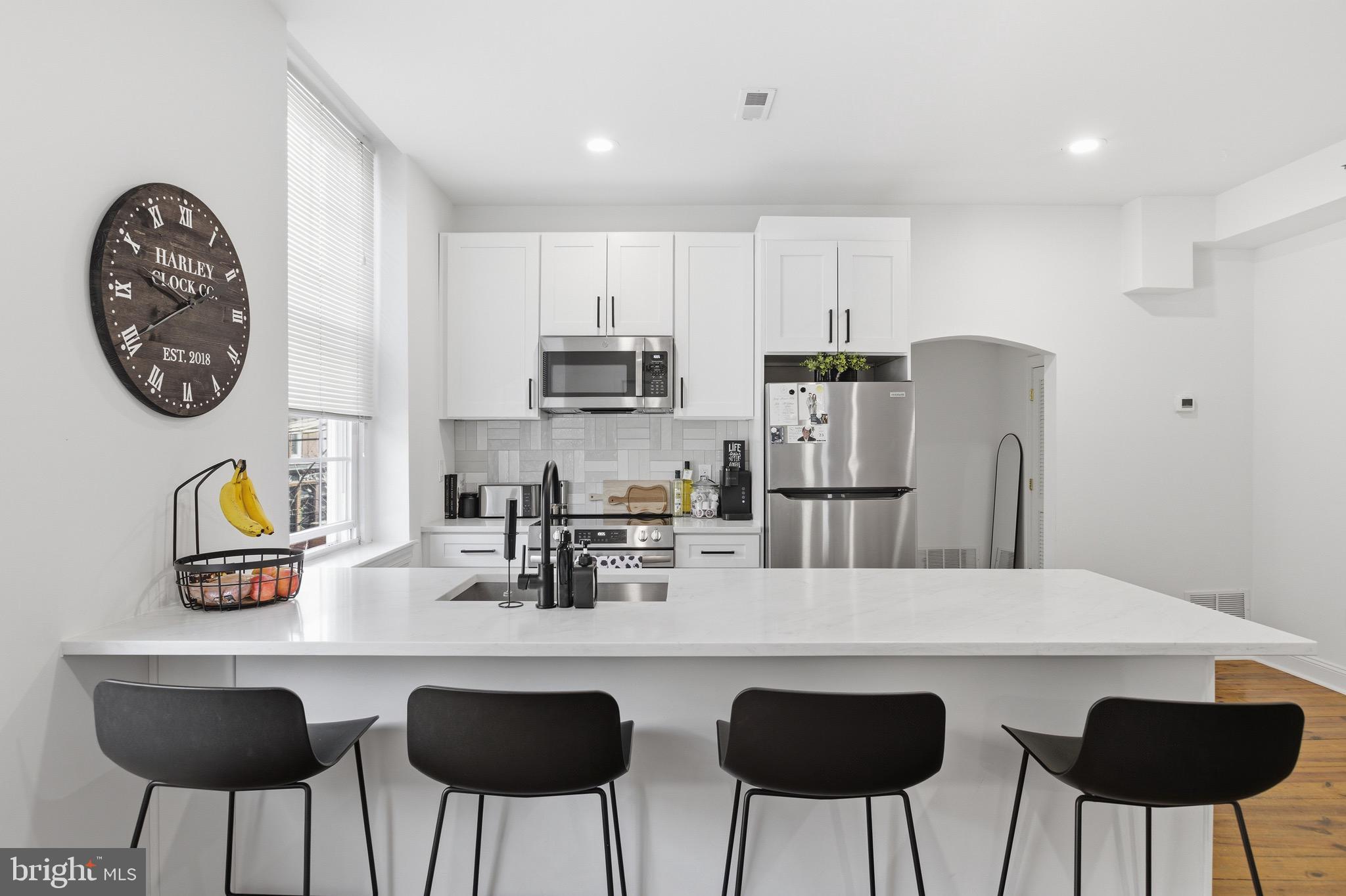 700 South 2nd Street, Unit B1 Philadelphia, PA 19147 - Photo 3 of 18 a kitchen with stainless steel appliances a table chairs and a refrigerator