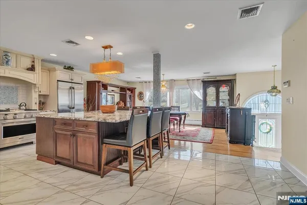 a kitchen with stainless steel appliances granite countertop a stove top oven a sink dishwasher and white cabinets with wooden floor