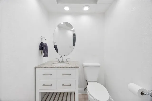 a bathroom with a granite countertop toilet sink and mirror