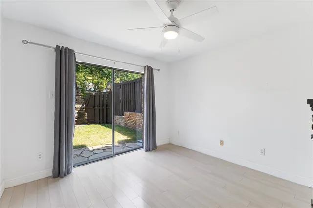 an empty room with a floor to ceiling window and a ceiling fan
