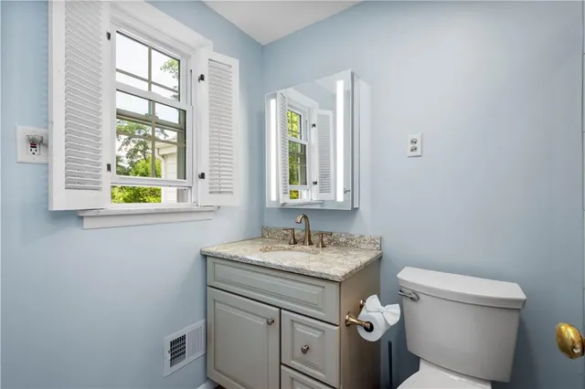 a bathroom with a granite countertop toilet sink and window