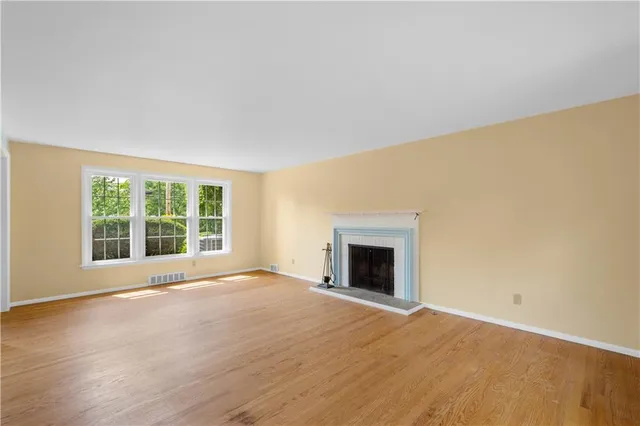 a view of empty room with wooden floor and a window