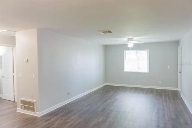 an empty room with wooden floor and windows