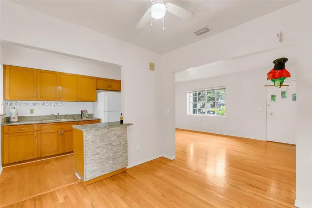 a view of a kitchen with wooden floor and a ceiling fan