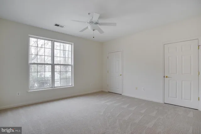 an empty room with chandelier fan and windows