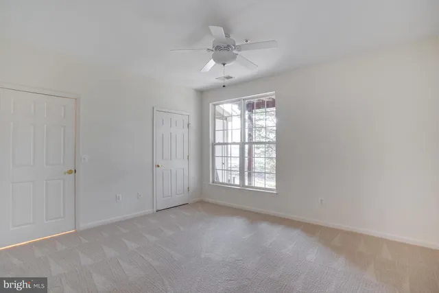 an empty room with windows and ceiling fan