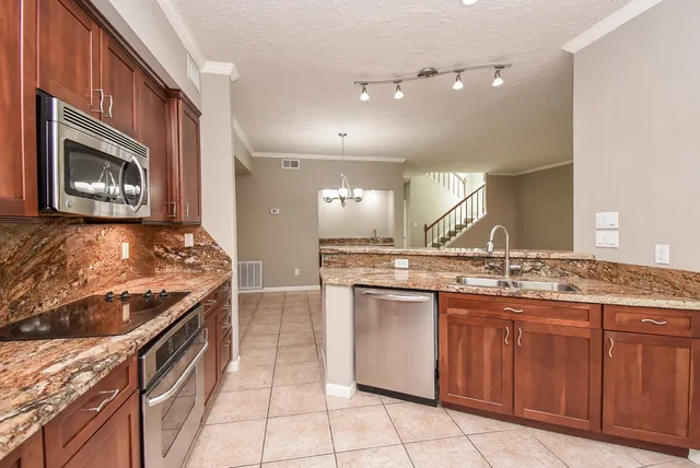 a kitchen with stainless steel appliances granite countertop a stove a sink and a microwave