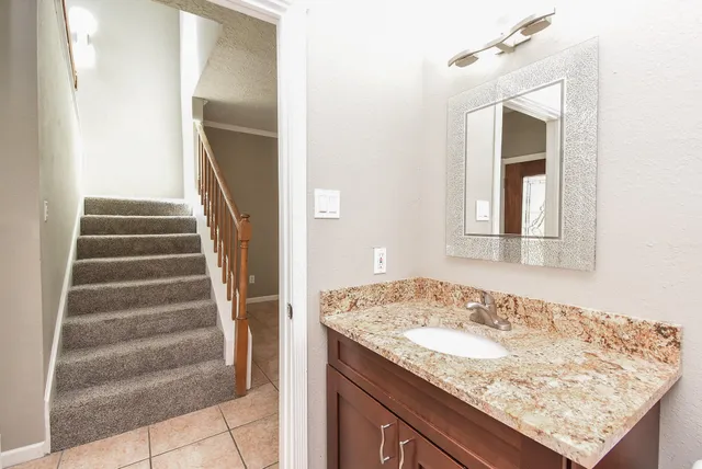 a bathroom with a granite countertop sink and a mirror