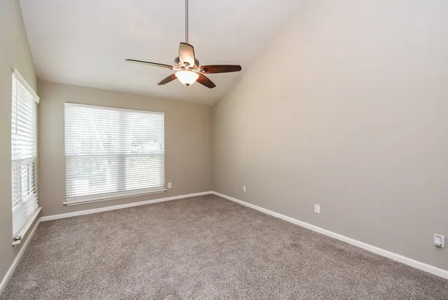 an empty room with windows and fan