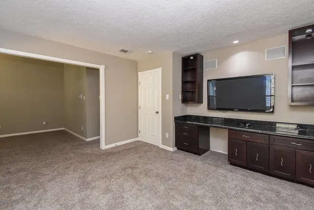 a living room with stainless steel appliances kitchen island granite countertop a refrigerator and a stove top oven