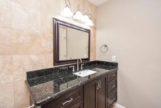 a bathroom with a granite countertop sink and a mirror