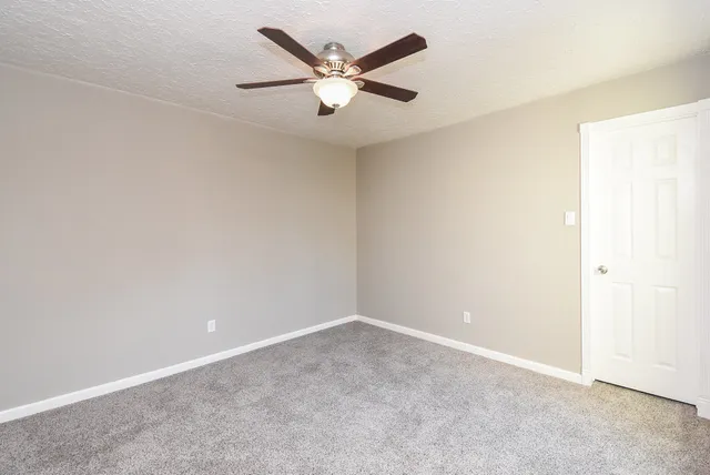 an empty room with closet and ceiling fan