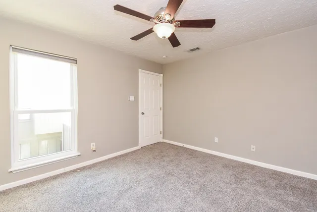 an empty room with a window and a fan
