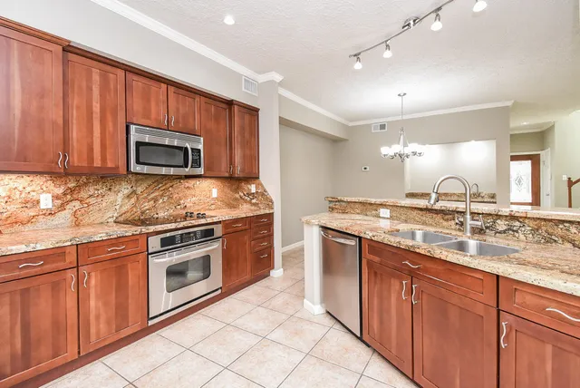 a kitchen with stainless steel appliances granite countertop wooden cabinets a stove top oven a sink and dishwasher